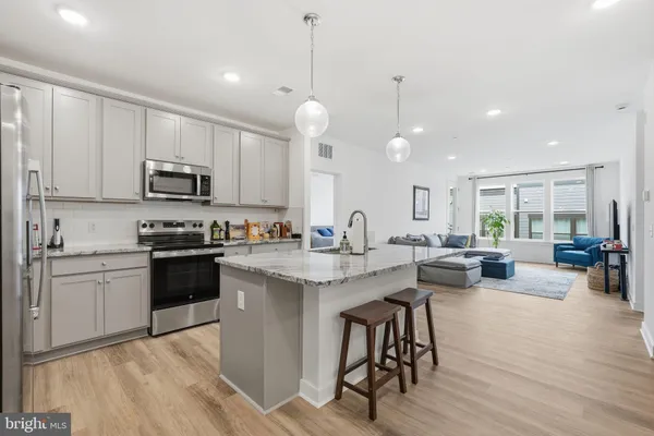 a kitchen with stainless steel appliances granite countertop a stove a sink dishwasher a microwave oven and a dining table with wooden floor