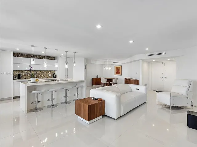 a large white room with kitchen island a sink and white cabinets