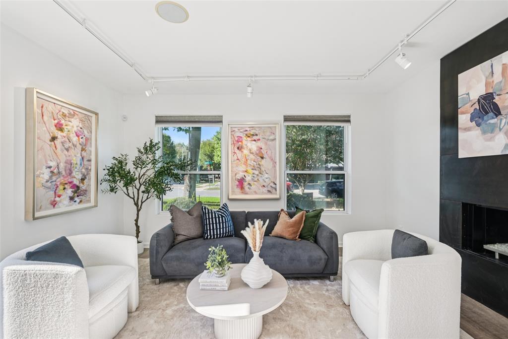 4102 Bowser Avenue, Unit 1 Dallas, TX 75219 - Photo 2 of 33 Sun-filled living room anchored by a bold modern fireplace and corner windows with leafy neighborhood views.