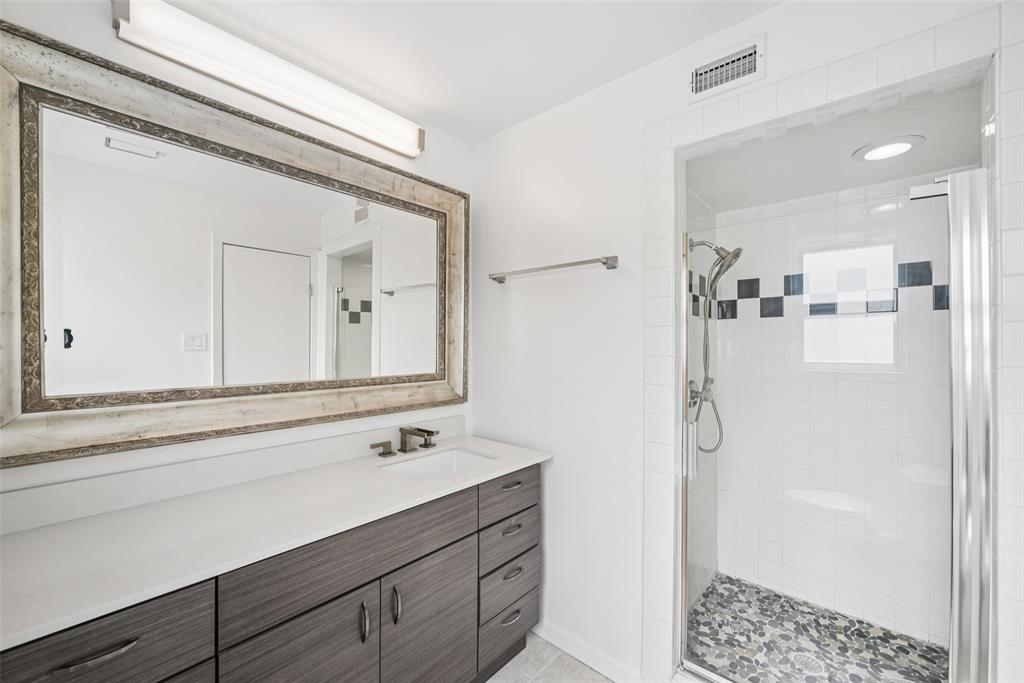 4102 Bowser Avenue, Unit 1 Dallas, TX 75219 - Photo 27 of 33 Updated bath features a wide vanity, oversized framed mirror, and walk-in shower with pebble-tile floor.