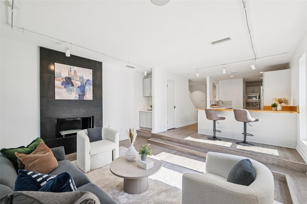 4102 Bowser Avenue, Unit 1 Dallas, TX 75219 - Photo 6 of 33 Natural light pours through multiple exposures, highlighting the airy connection between living, dining, and kitchen.