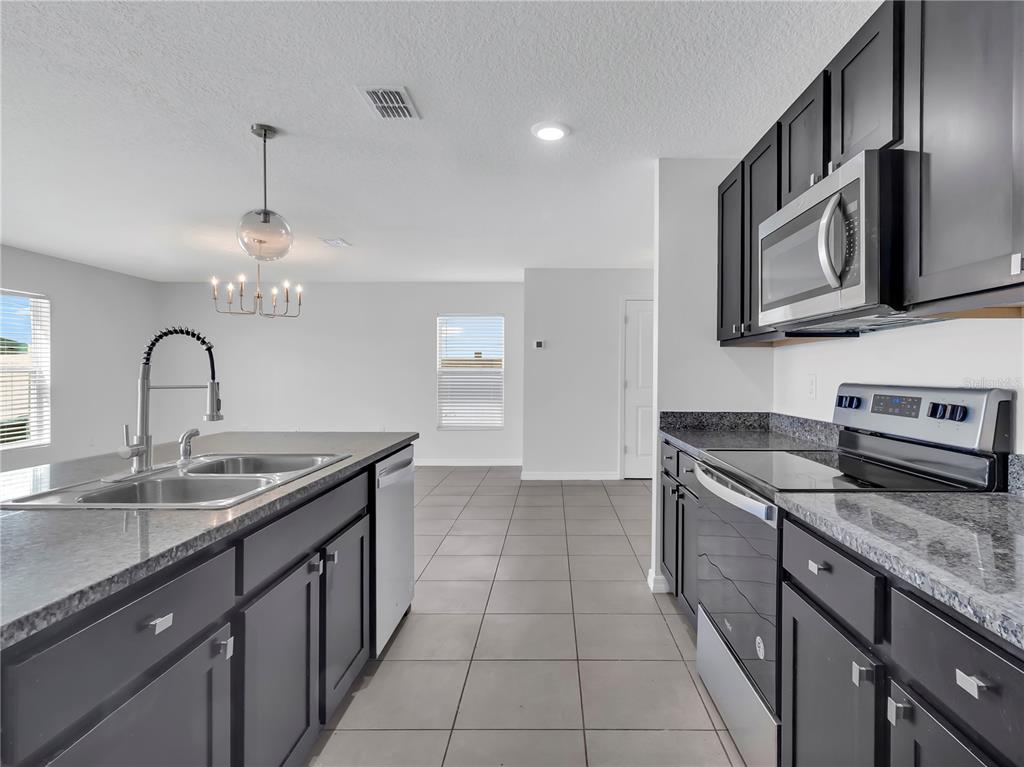 602 Olive Conch Street Ruskin, FL 33570 - Photo 8 of 23 a kitchen with stainless steel appliances granite countertop a sink stove and cabinets