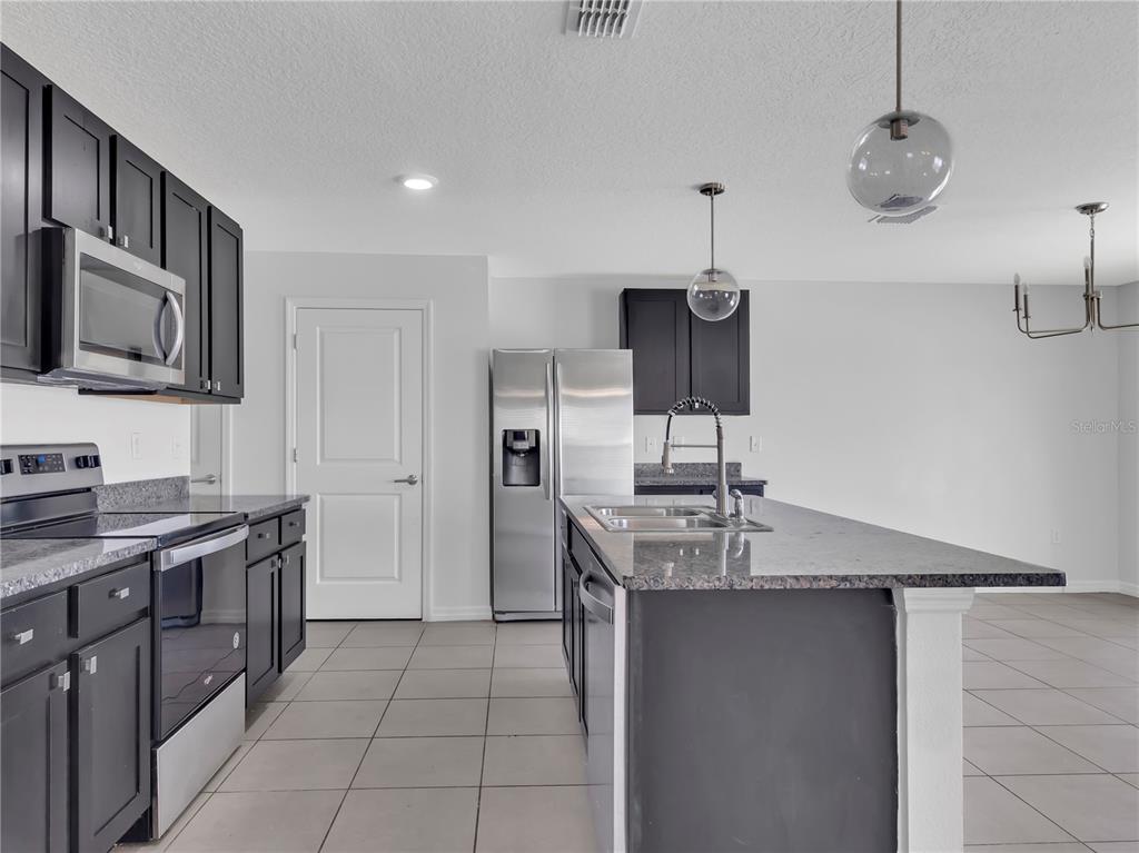 602 Olive Conch Street Ruskin, FL 33570 - Photo 9 of 23 a kitchen with stainless steel appliances granite countertop a sink and a refrigerator