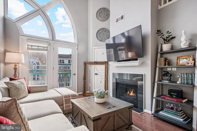 a living room with furniture a fireplace a flat screen tv and a large window