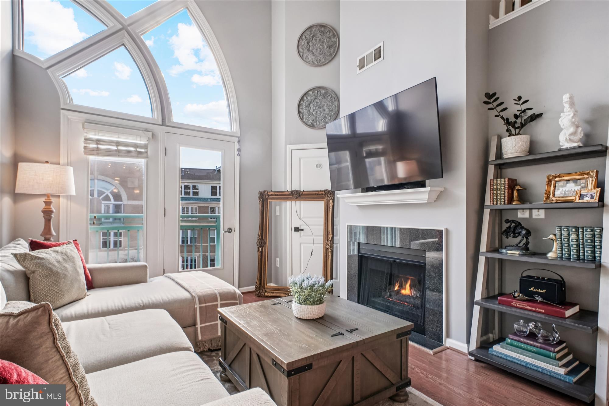 a living room with furniture a fireplace a flat screen tv and a large window