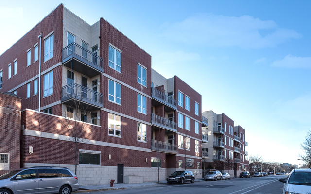 a front view of a building with lot of cars and trees