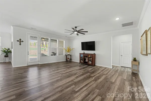 a view of a livingroom with a flat screen tv wooden floor and a ceiling fan