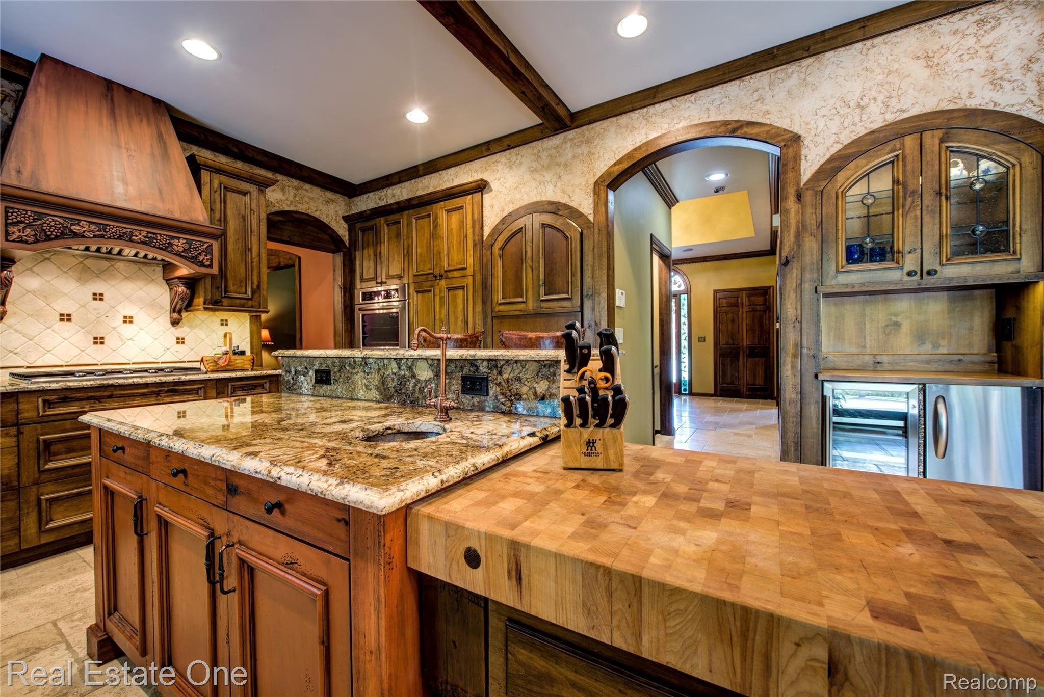 3274 Quail Ridge Circle Rochester, MI 48309 - Photo 24 of 74 Kitchen granite counters, marble backsplash, island with copper bar sink, mixer storage lift, butcher block work station, ice maker, wine refrigerator