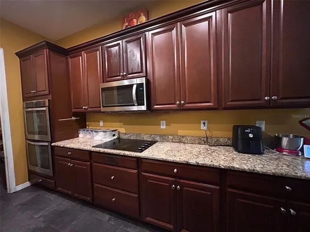 a kitchen with granite countertop wooden cabinets a refrigerator and a sink