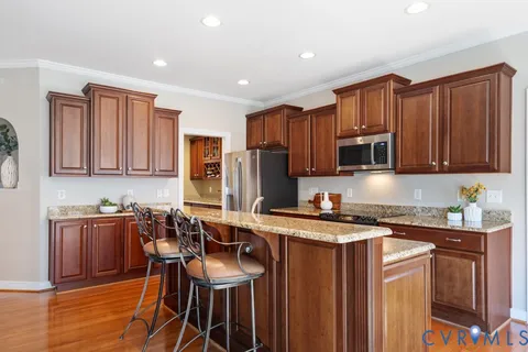 a kitchen with stainless steel appliances granite countertop a sink a stove a refrigerator cabinets and wooden floor