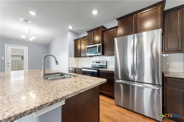 a large kitchen with granite countertop a sink and a refrigerator