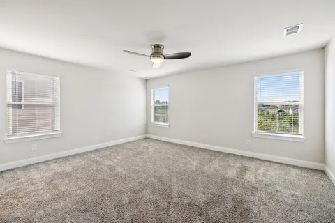 an empty room with windows and fan