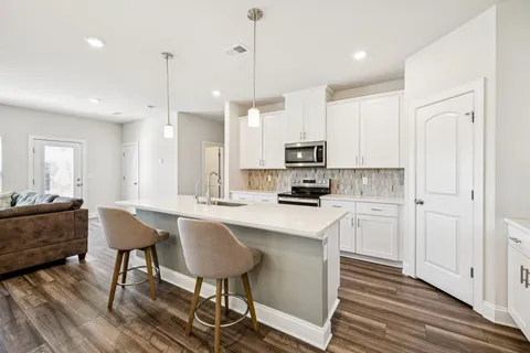 a kitchen with stainless steel appliances kitchen island granite countertop a table chairs microwave and sink