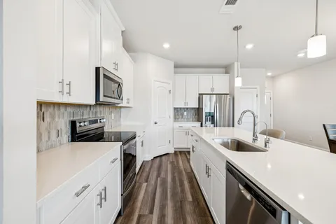 a kitchen with stainless steel appliances a sink a stove top oven a refrigerator a counter top space and cabinets