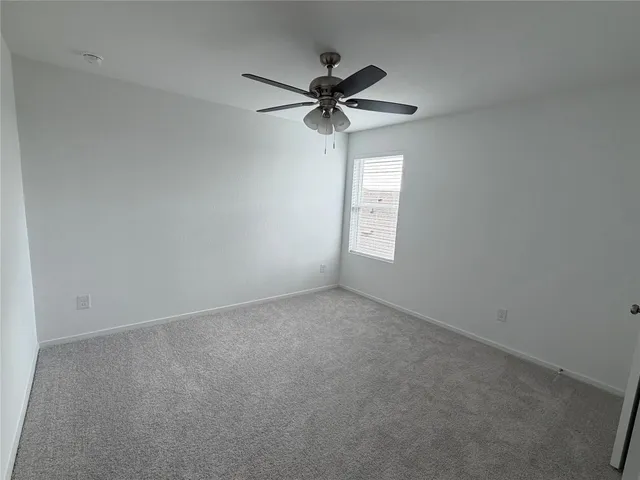 an empty room with a chandelier fan and windows