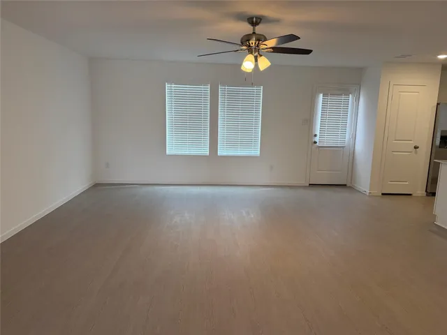 an empty room with windows and ceiling fan