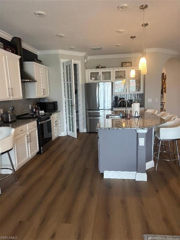 1599 Marton Court Naples, FL 34113 - Photo 2 of 22 a kitchen with stainless steel appliances kitchen island granite countertop a refrigerator a stove top oven and a dining table with wooden floor