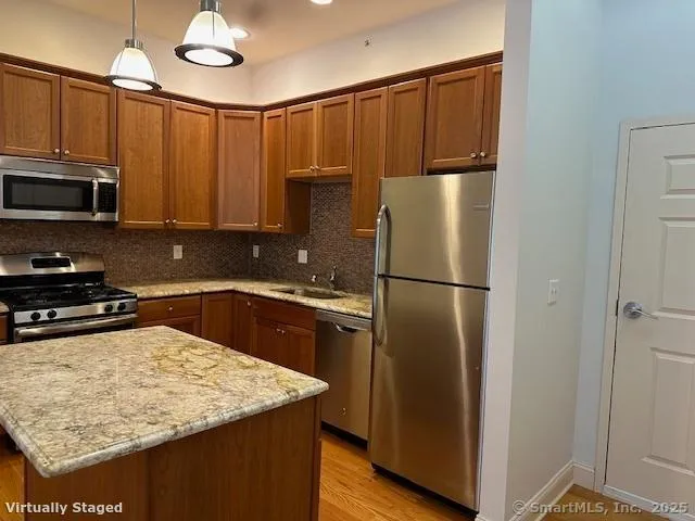 a kitchen with stainless steel appliances granite countertop a refrigerator a stove and a sink with wooden floor