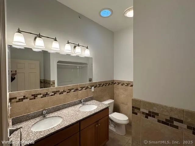 a bathroom with a granite countertop sink toilet and mirror