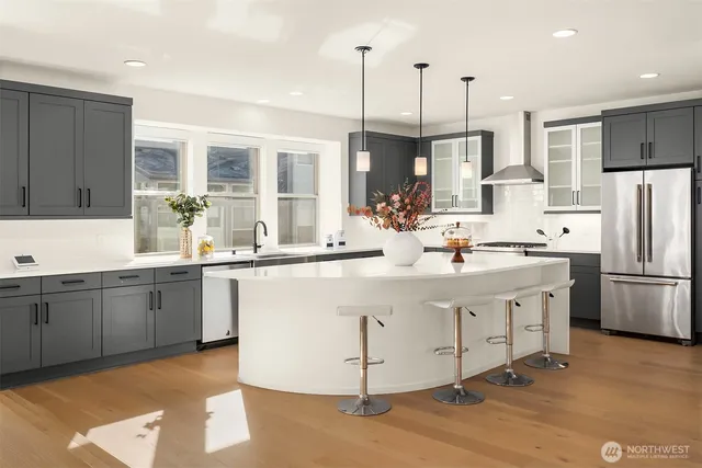 a kitchen with stainless steel appliances granite countertop a sink a stove a refrigerator and island with wooden floor