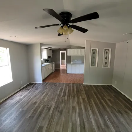 an empty room with wooden floor a ceiling fan and windows