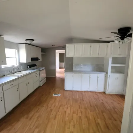 a large kitchen with a wooden floor and stainless steel appliances