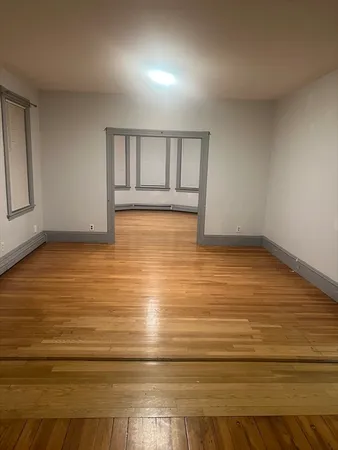a view of an empty room with wooden floor and cabinet