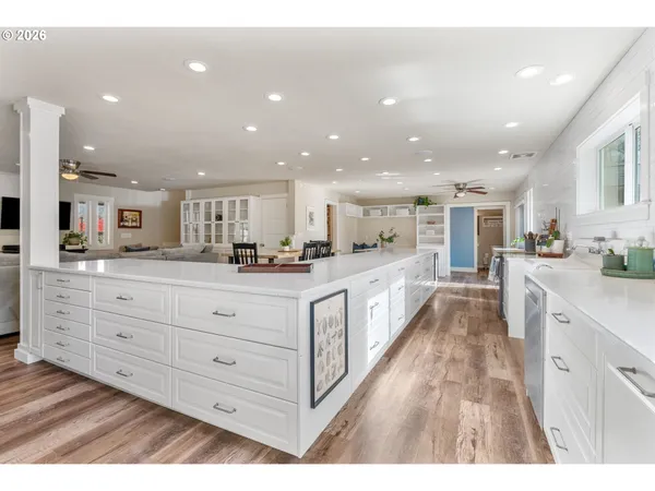 a large white kitchen with kitchen island a sink a center island stainless steel appliances and cabinets