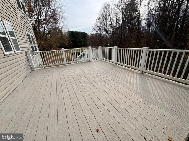 a view of deck with wooden floor and fence and trees around