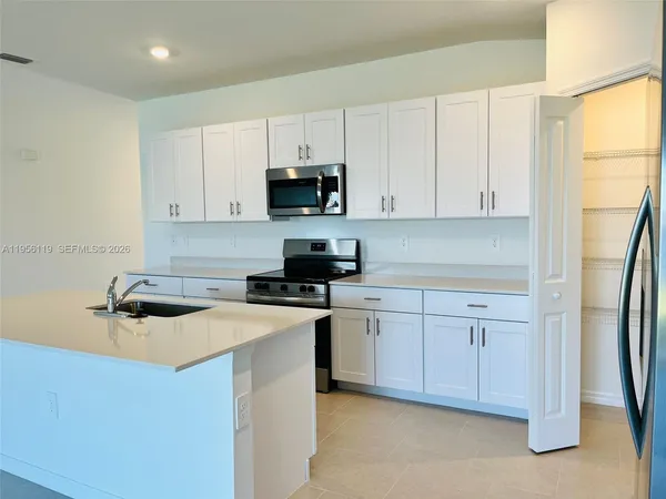 a kitchen with stainless steel appliances a sink a stove a refrigerator and cabinets