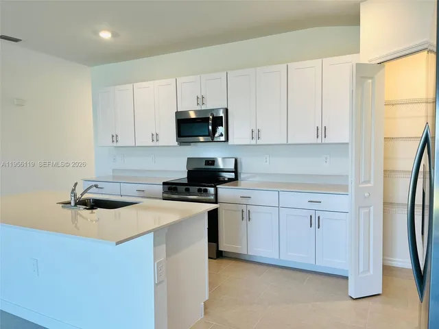 a kitchen with stainless steel appliances a sink a stove a refrigerator and cabinets