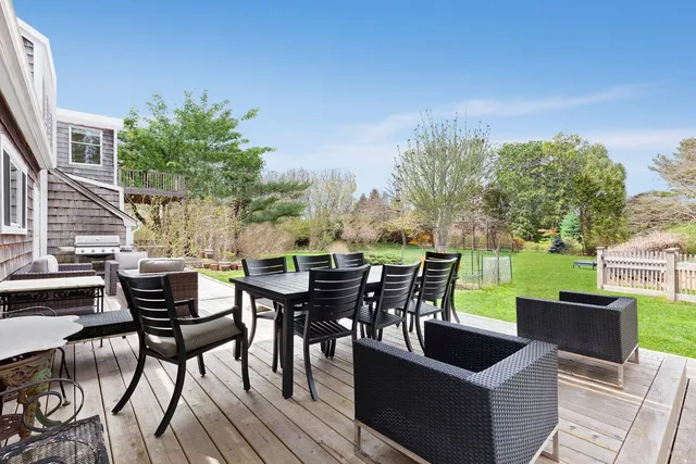 a view of a roof deck with table and chairs couches with wooden floor and fence