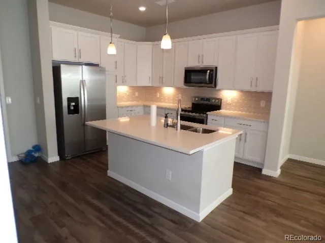 a kitchen with stainless steel appliances a refrigerator a stove a microwave oven with cabinets and wooden floor