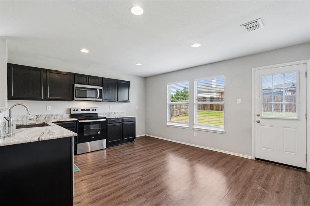 3005 Groveland Terrace Denton, TX 76210 - Photo 11 of 26 a large kitchen with stainless steel appliances granite countertop a stove a sink a refrigerator white cabinets and wooden floor