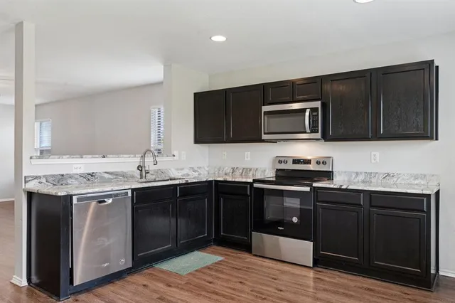 a kitchen with stainless steel appliances granite countertop wooden cabinets and sink