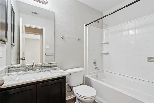 a bathroom with a granite countertop sink a toilet and shower