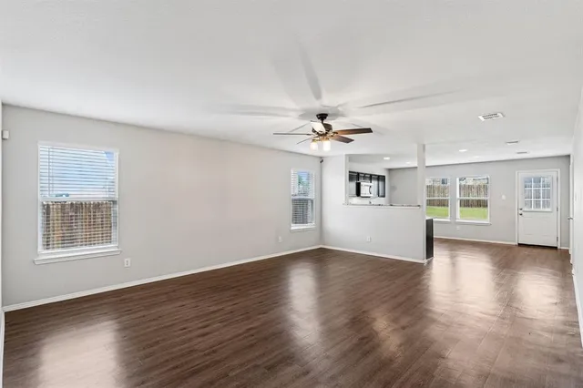 a view of an empty room with a window and wooden floor
