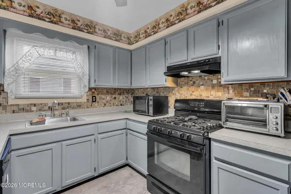 a kitchen with sink a stove and cabinets