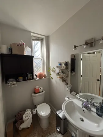 a bathroom with a sink mirror toilet and window