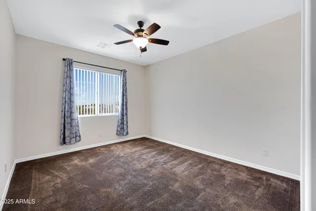 an empty room with windows and chandelier fan