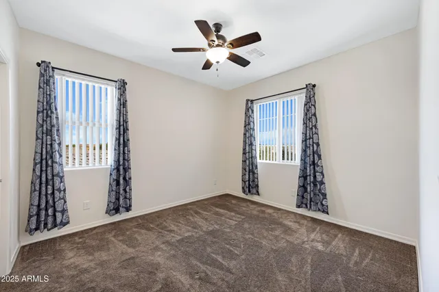 an empty room with ceiling fan and window