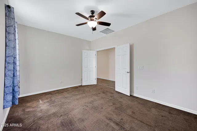 an empty room with ceiling fan and window