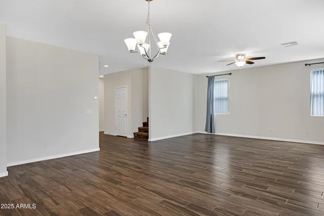 a view of an empty room with wooden floor and a chandelier