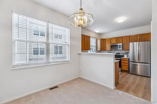 a kitchen with stainless steel appliances granite countertop a refrigerator a stove a sink dishwasher a dining table and chairs with wooden floor