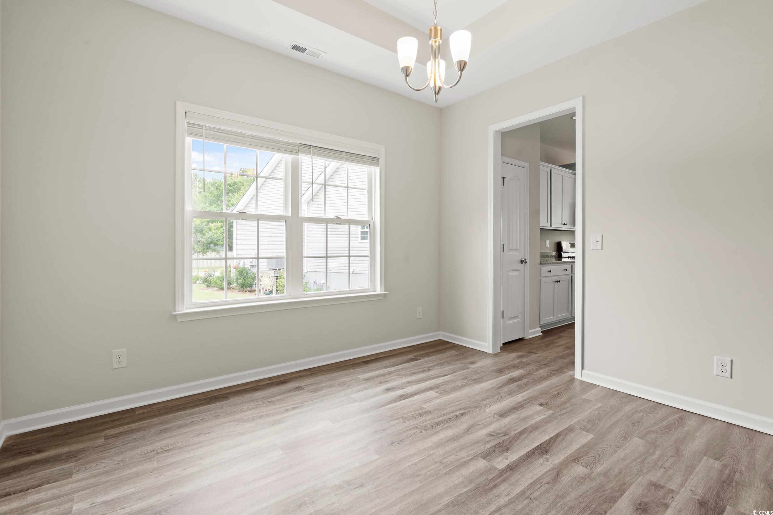 512 Charlton Boulevard Georgetown, SC 29440 - Photo 6 of 35 Empty room with a chandelier, light wood-style floors, and baseboards