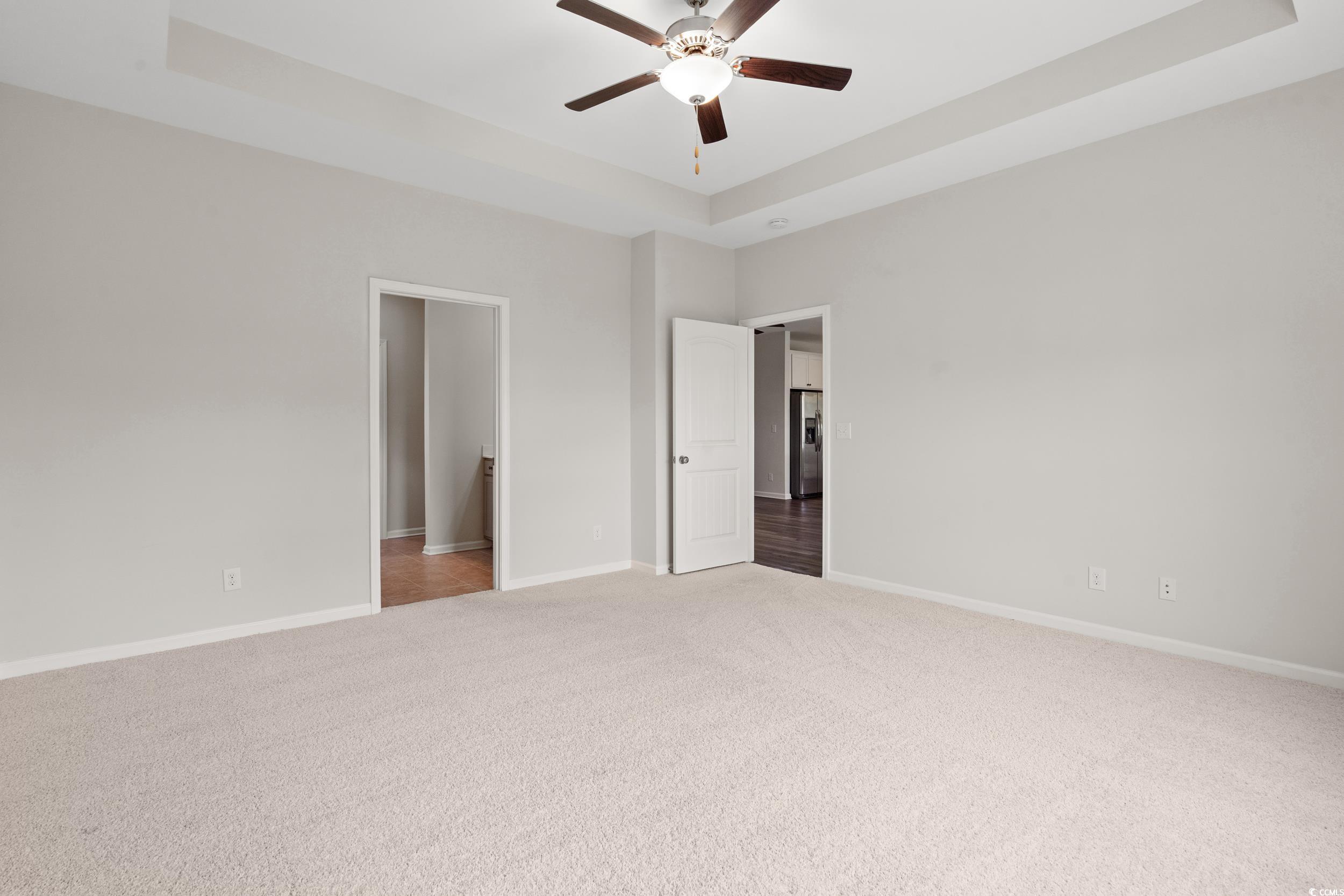 512 Charlton Boulevard Georgetown, SC 29440 - Photo 10 of 35 Unfurnished bedroom featuring light colored carpet, a tray ceiling, baseboards, and a ceiling fan
