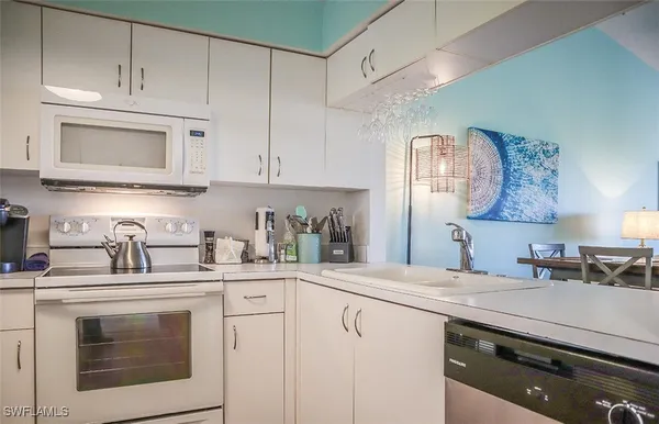 a kitchen with granite countertop white cabinets white stainless steel appliances and sink
