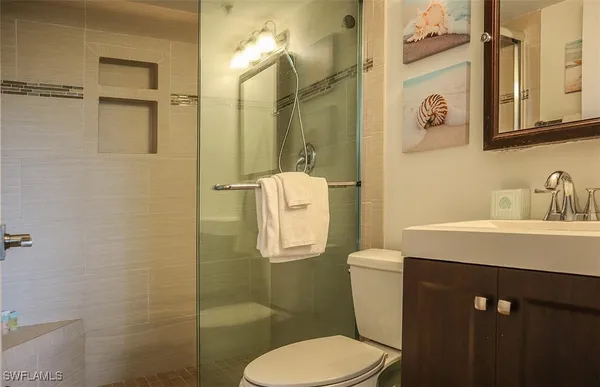 a bathroom with a sink a mirror a toilet and shower