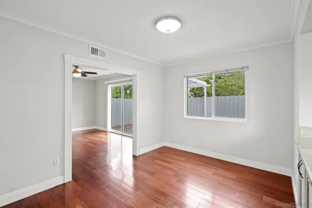 an empty room with wooden floor fan and windows