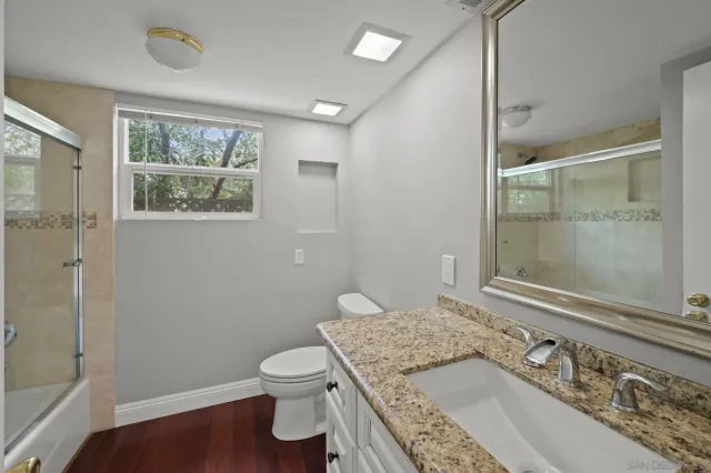 an empty room with wooden floor chandelier fan and windows